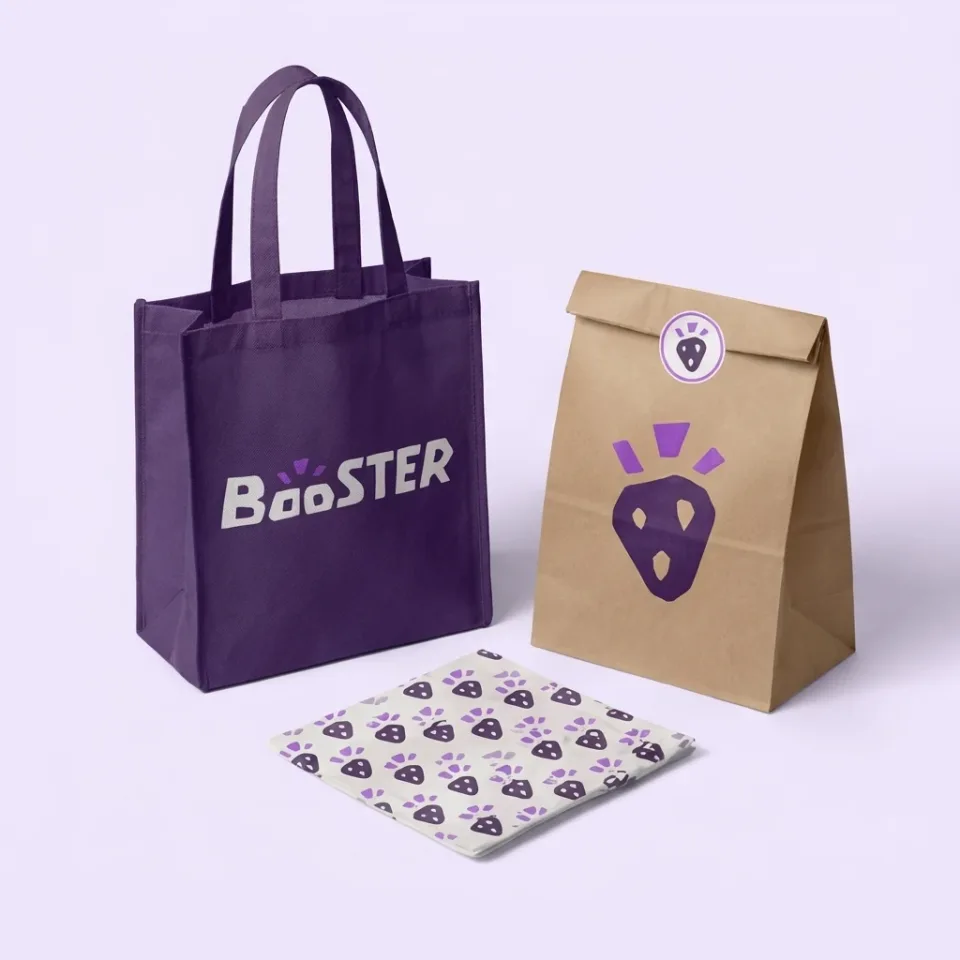 Booster identity applied to a purple tote, kraft takeaway bag, and patterned wrapper